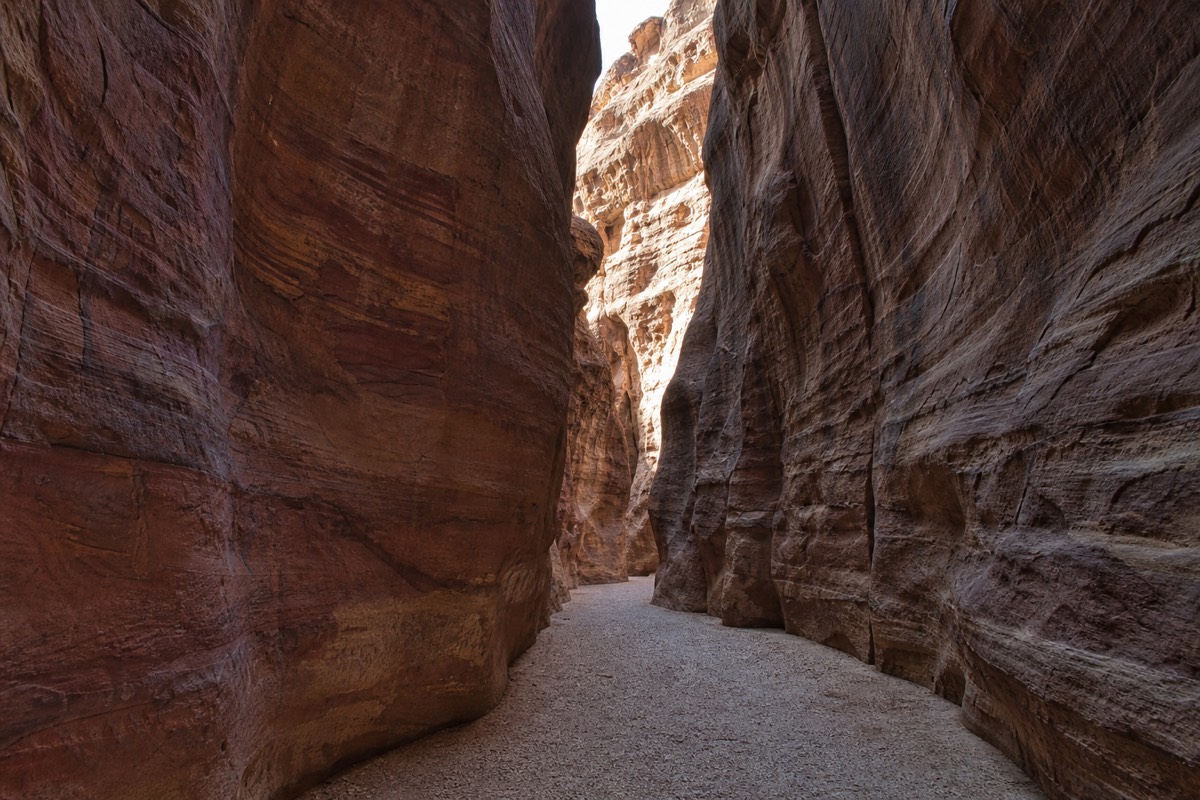 A Jordan Pass ticket booklet held up in front of Petra's Treasury facade
