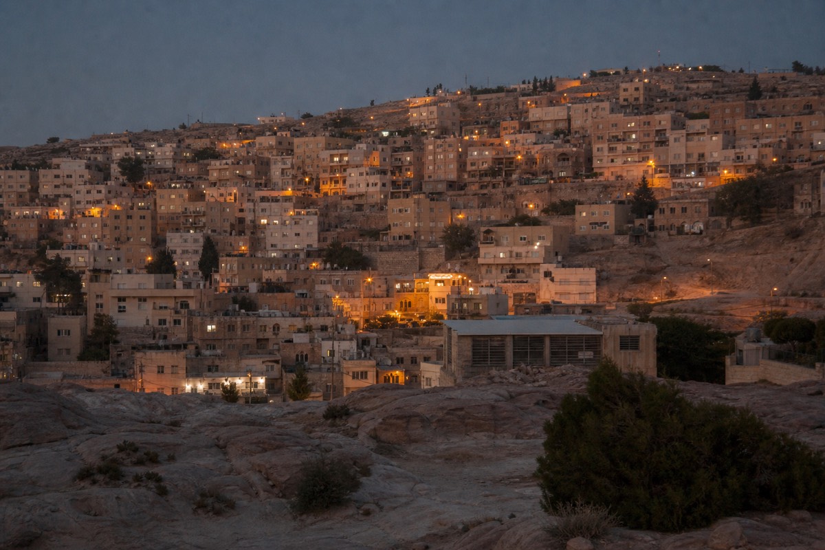 Hillside hotels and stone buildings in the town of Wadi Musa overlooking the valley leading toward Petra at dusk