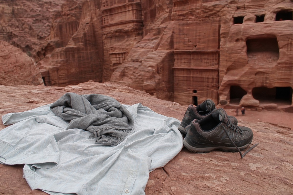 A woman in loose long sleeves and a light scarf walking through a sandstone canyon in Jordan